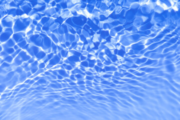 Blue water with ripples on the surface. Defocus blurred transparent blue colored clear calm water surface texture with splashes and bubbles. Water waves with shining pattern texture background.