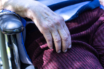 gros plan sur la main d'une personne âgée qui est assise dans un fauteuil roulant