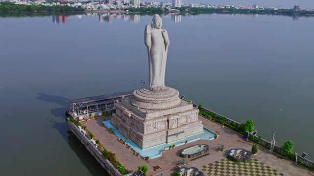 buddha statue with ambedkar statue and buildings  in the background with reflections in hussain sagar lake, hyderabad, telangana, india, 4k drone orbit shot