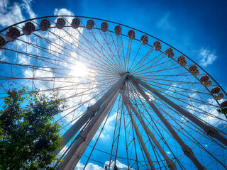 Ein Blickwinkel von unten auf ein riesiges, weißes Riesenrad, das sich vor einem klaren, blauen...
