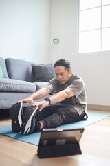 Active and fit Asian man warm up and stretching before doing exercise routine at living room.