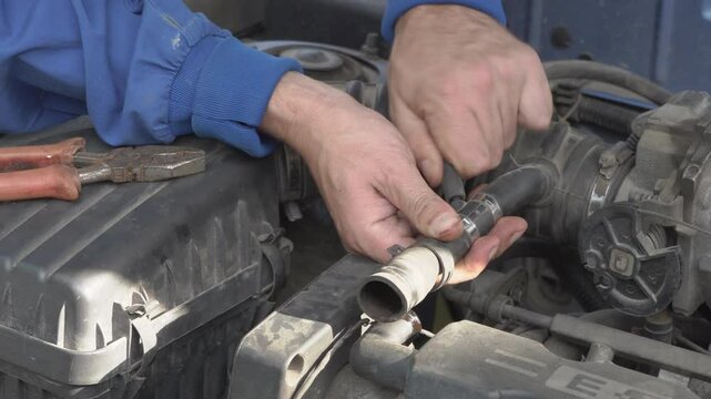 disconnect the air pipe in the car, the man opened the hood of the car and is repairing it