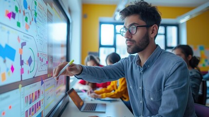 Male teacher showing something on screen of computer to the students in classroom while they working on individualized projects
