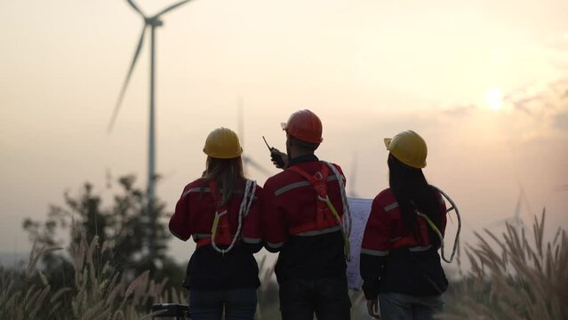 Young man and woman maintenance engineer team. two engineer operate wind turbine. Engineer and worker discussing on a wind turbine farm. Wind Turbine. Maintenance Workers. renewable energies.