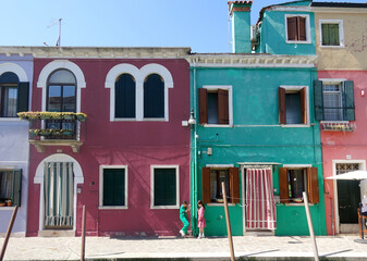 Green and Pink girls dancing in front of colorful buildings on the Island of Burano Venice Italy