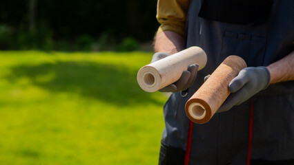 A man in gloves holds two dirty water filters, illustrating contamination levels.