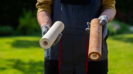 Plumber in gloves showing two dirty drinking water filters.
