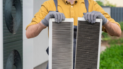 Plumber with gloves showing two heavily clogged air filters from a home air conditioning system.