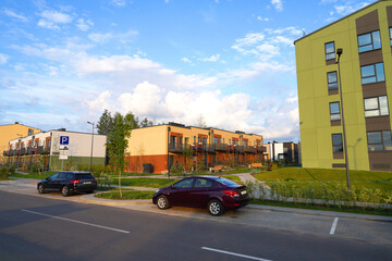 Fototapeta premium Modern European complex of apartment buildings. Street in New modern housing estate. Twin house at road in Urbanization. Finished new townhouses. Еxterior townhomes. Car on parking lot at Townhouse.