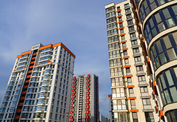 Naklejka premium Facade building. Modern building and houses against blue sky. Colorful buildings with glass windows, balconies. Buildings architecture. Skyline Skyscrapers. Urban Residential building exterior.