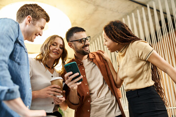 A group of colleagues in a coworking space, gathered around a smartphone screen, engaged in digital collaboration.