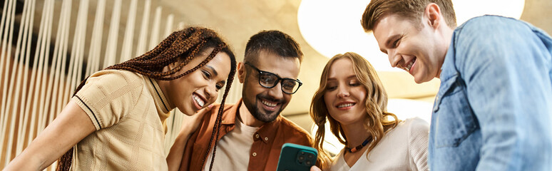 A group of colleagues in a coworking space huddle together, captivated by the content on a...