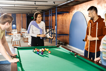A group of colleagues from a startup team enjoying a game of pool in a modern business setting.