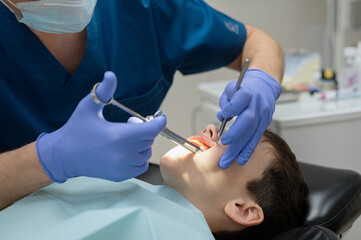 The dentist gives an anesthetic injection into the gum to a boy who is sitting in a dental chair. Dental treatment.
