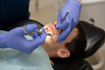 The dentist gives an anesthetic injection into the gum to a boy who is sitting in a dental chair. Dental treatment.