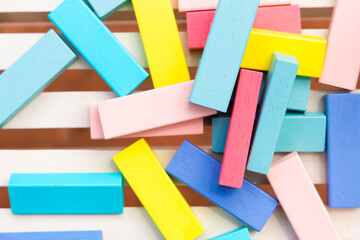 colored wooden bricks scattered on a brick red and white striped background