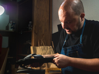 Shoemaker analyzing the shoes he has to fix. small businesses, trades.