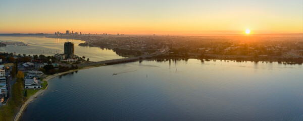 Canning Bridge and river in Perth, Australia as the sun rises on the horizon, with still water