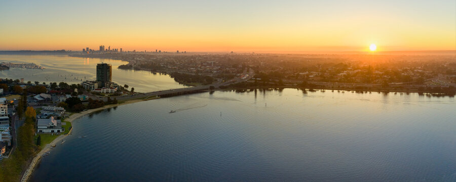 Canning Bridge and river in Perth, Australia as the sun rises on the horizon, with still water