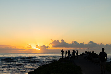 Silhouette of group of people gathering to watch the sunrise from the breakwall at Brunswick Heads