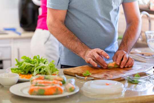 Aussie Man making fresh Vietnamese spring rolls on kitchen bench