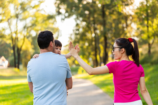 mixed race family of three high five while on walk