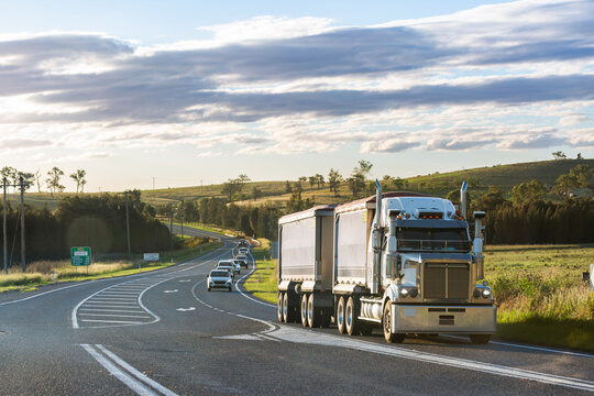 Truck driving on rural road in country followed by cars of mine shift workers heading home
