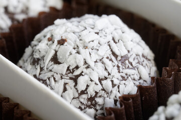 Delicious handmade round chocolate candy sprinkled with coconut in a paper tartlet. Photo. Macro. Selective focus