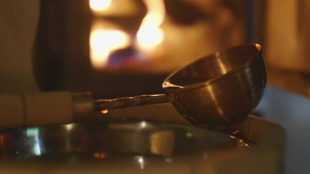 Close-up of a wooden bucket with a ladle against the background of a burning fire in the fireplace in the bathhouse. Atmosphere in sauna.