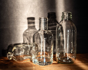 Still life with glass bottles, quiet shadows in the background, soft evening light