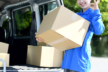 外で荷物を運ぶ配送ドライバーの女性
