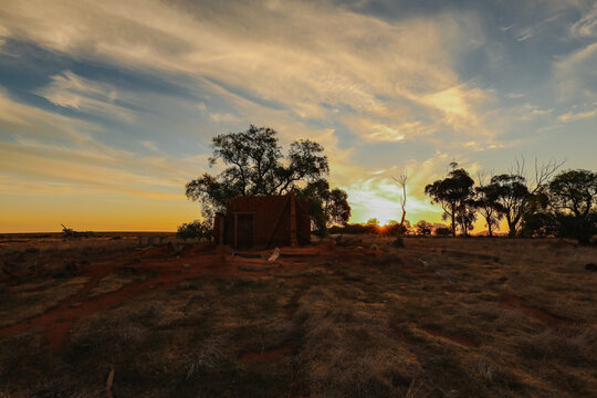 Ruins of abandoned mud brick home on rural property at sunset