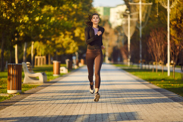 Woman runner exercises in park running healthy lifestyle front view. With each stride embodies...