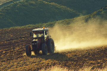 Fototapeta premium Tractor Working the Soil in a Field on a Sunny Day