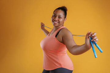 Jumping rope, standing. African American woman is in the studio against yellow background