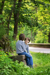 Sweet twin brothers, children sitting on bench in park