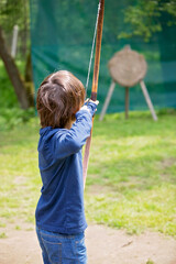 Portrait of child playing with bow and arrows, archery shoots a bow at the target