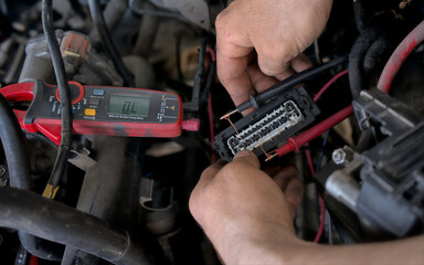 A skilled auto electrician using diagnostic tools to test voltage levels in a car's electrical system, ensuring accurate troubleshooting and repairs. Auto service.