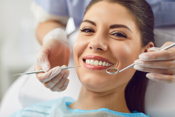 Portrait of a happy patient during a visit to the dentist. The doctor is checking teeth using a dental instrument, ensuring proper oral care and thorough examination in the dentistry clinic.