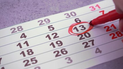 Plan a work week. Circle and strike through calendar dates. Write with a red felt-tip pen. Planning visit doctor, meeting, party birth day. Hand planning dates. Friday the thirteenth
