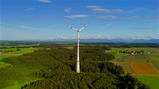 Aerial view of wind turbine in Bavaria, Ebersberg region, Germany. Luftaufnahme einer Windturbine vor dem Hintergrund der Alpen in Bayern, Deutschland. Wind turbine on golf course overlooking alps. 