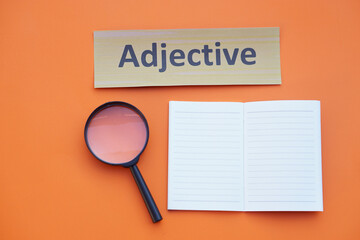 Magnifying glass, paper notebook and Adjective card. Concept. Education material.Teaching aid....