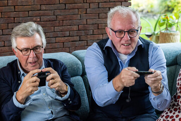 Two elderly men are enthusiastically playing video games, illustrating the joy of gaming at any age.