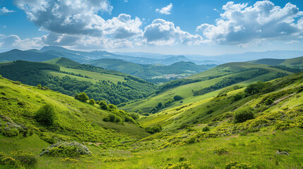 Naklejka premium Scenic view of rolling hills, lush green valleys, scattered trees, and blue sky with fluffy clouds