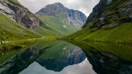Obraz premium A serene lake nestled amidst the towering mountains of Norway, reflecting the beauty of the landscape in its still waters.