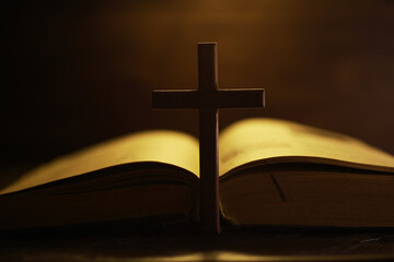 Wooden Cross Silhouette on Open Bible with Warm Lighting