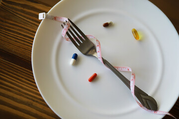Diet and Nutrition Concepts: Fork Wrapped with Measuring Tape and Pills on Plate