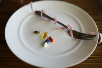 Diet Concept: Pills and Measuring Tape on a Plate with Fork