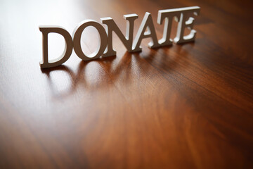 Wooden Donate Sign on Polished Wood Floor Representing Charity and Giving