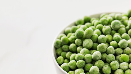 A bowl of frozen green peas on a white background. Fresh and healthy vegetable